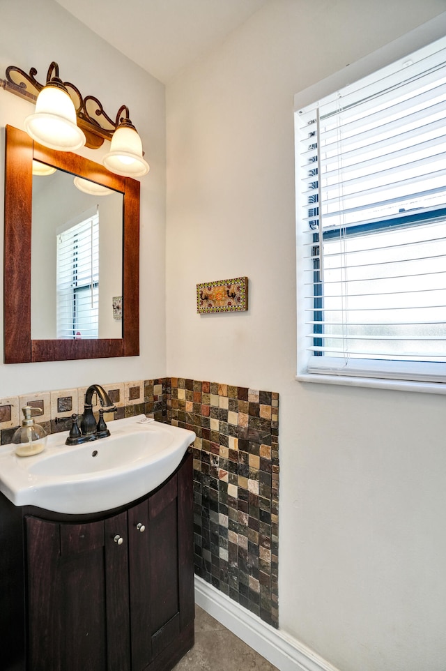 bathroom with a wealth of natural light, vanity, and tile walls