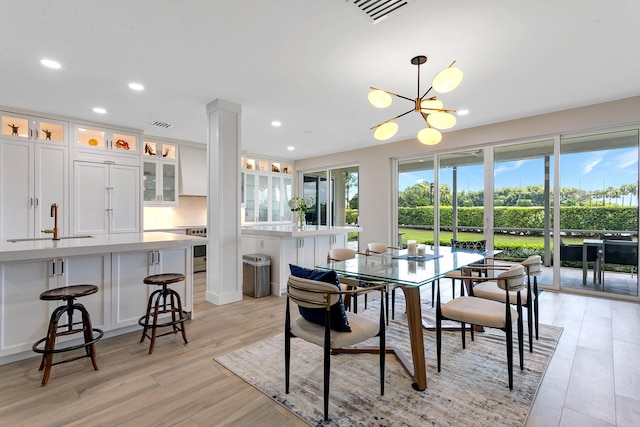 dining area featuring a notable chandelier, plenty of natural light, sink, and light wood-type flooring