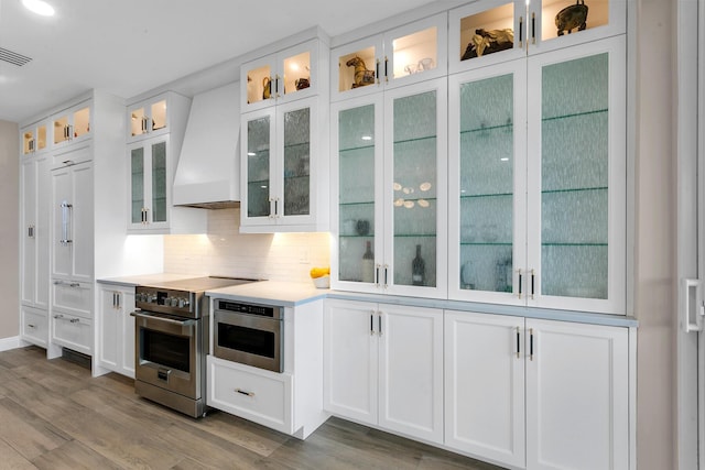 kitchen with white cabinetry, custom range hood, and electric stove