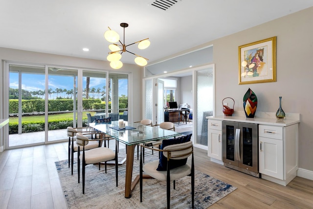 dining room featuring beverage cooler, a chandelier, and light wood-type flooring