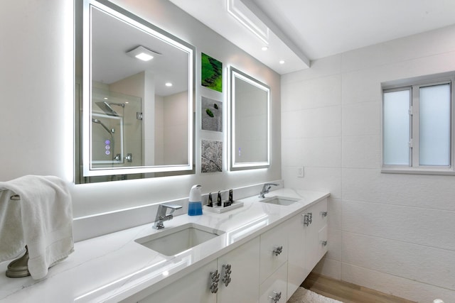 bathroom with vanity, a shower with shower door, and tile walls