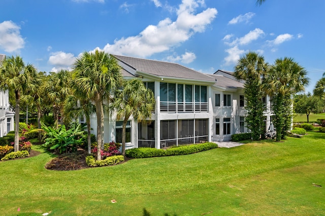 back of house with a sunroom and a lawn