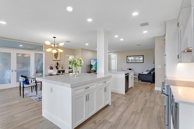 kitchen featuring hanging light fixtures, a kitchen island, white cabinets, and light wood-type flooring