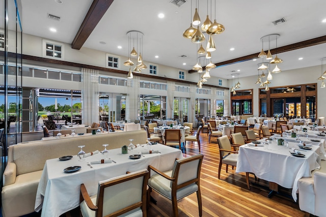 dining space with beam ceiling, plenty of natural light, french doors, and light wood-type flooring