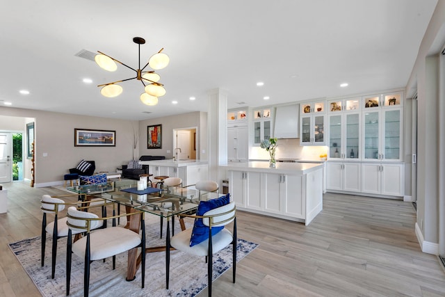 dining space with sink, an inviting chandelier, and light hardwood / wood-style floors