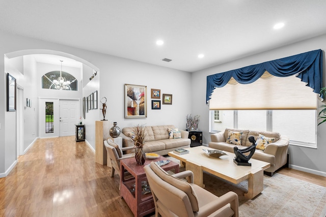 living room with an inviting chandelier, a healthy amount of sunlight, and light wood-type flooring