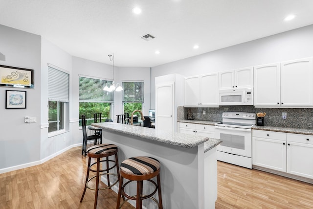 kitchen featuring a chandelier, decorative backsplash, white appliances, and light hardwood / wood-style flooring