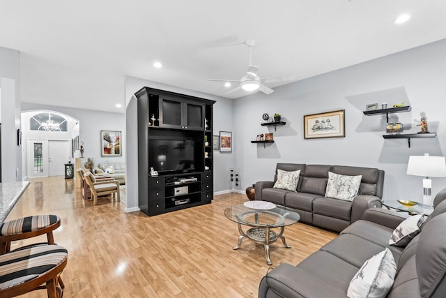 living room featuring ceiling fan with notable chandelier and hardwood / wood-style flooring