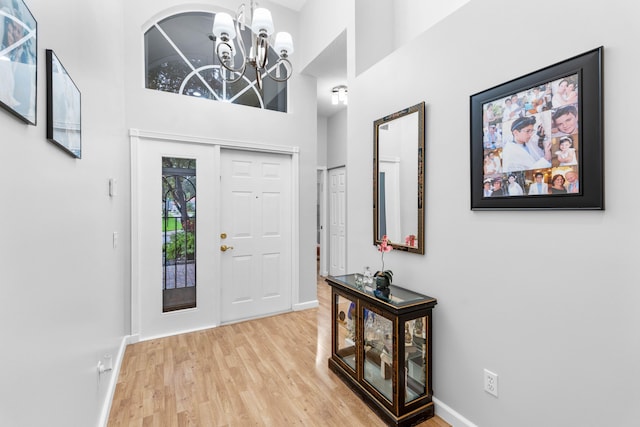 foyer with a high ceiling, hardwood / wood-style flooring, and an inviting chandelier