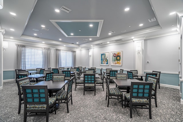 dining space with a tray ceiling, carpet floors, and ornamental molding