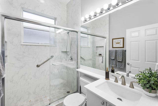 bathroom featuring vanity, a shower with shower door, and toilet