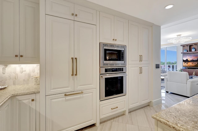 kitchen featuring white cabinets, decorative backsplash, light stone countertops, and stainless steel appliances