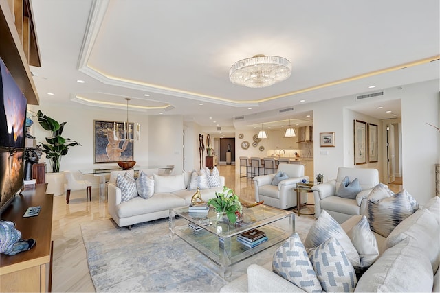 living room featuring a raised ceiling and an inviting chandelier