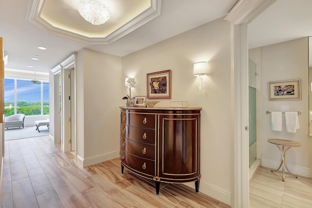 corridor featuring a raised ceiling and crown molding