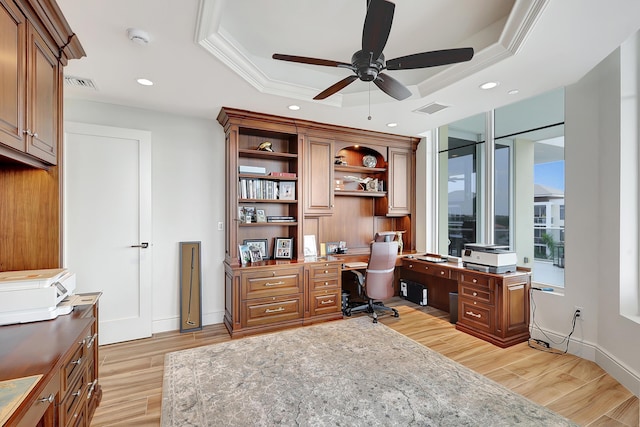 office area with light wood-type flooring, a raised ceiling, ceiling fan, and crown molding