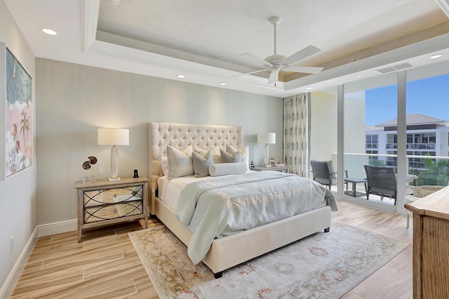 bedroom with ceiling fan, access to exterior, and a tray ceiling