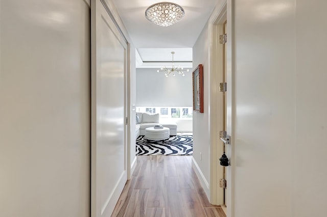 corridor with light hardwood / wood-style flooring and a notable chandelier