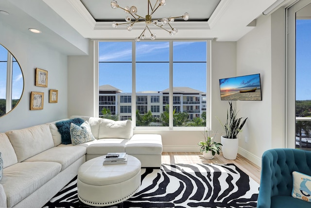 living room featuring hardwood / wood-style floors, a chandelier, ornamental molding, and a tray ceiling