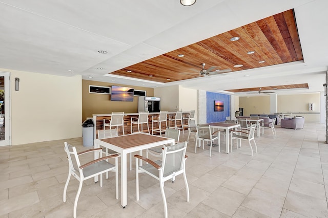 dining space with ceiling fan, wooden ceiling, and a tray ceiling