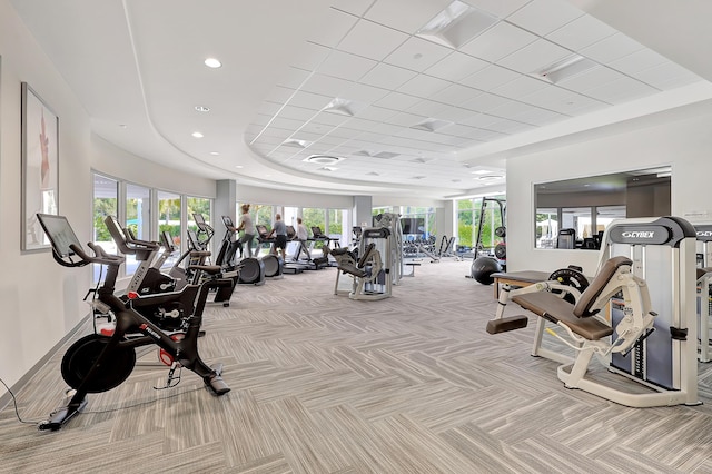 workout area with light carpet and a raised ceiling