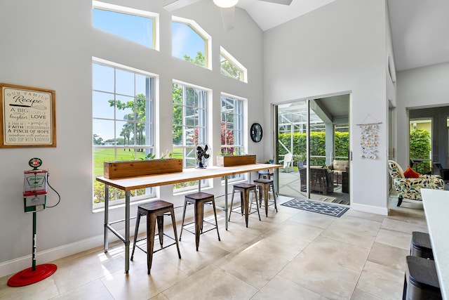 tiled dining area featuring high vaulted ceiling, ceiling fan, and a wealth of natural light