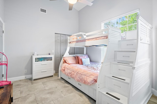 tiled bedroom featuring a towering ceiling, a closet, and ceiling fan