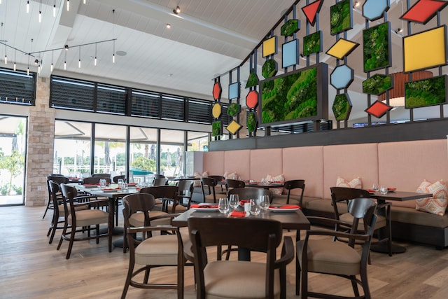 dining area with beamed ceiling, high vaulted ceiling, and light hardwood / wood-style flooring