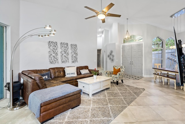 living room with light tile patterned floors, high vaulted ceiling, and ceiling fan with notable chandelier