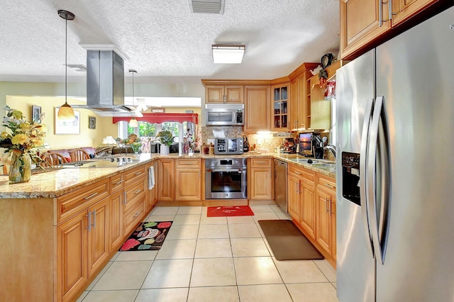 kitchen with light tile patterned floors, hanging light fixtures, stainless steel appliances, island range hood, and light stone countertops