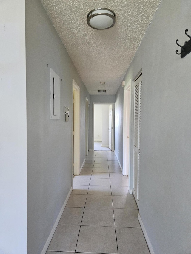 corridor featuring light tile patterned floors and a textured ceiling