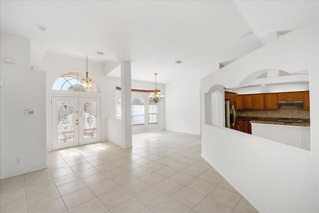 tiled foyer with french doors and an inviting chandelier