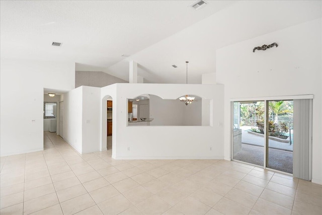 tiled spare room featuring high vaulted ceiling and an inviting chandelier