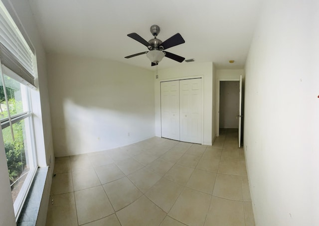 unfurnished bedroom with ceiling fan, a closet, and light tile patterned flooring