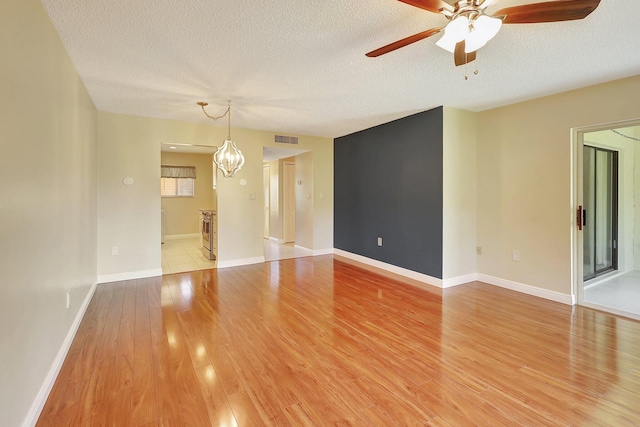 unfurnished room featuring hardwood / wood-style floors, ceiling fan with notable chandelier, and a textured ceiling