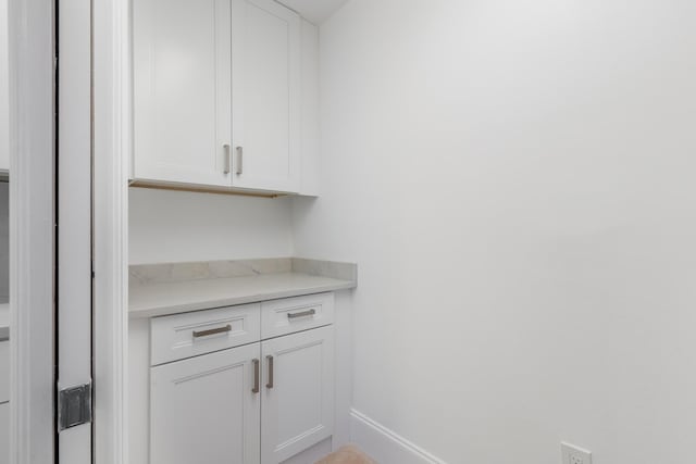 bar with white cabinetry and light stone counters