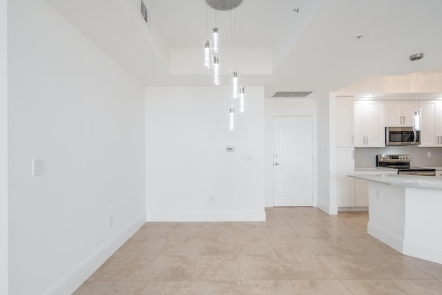 kitchen featuring light tile patterned floors, white cabinets, decorative light fixtures, and appliances with stainless steel finishes