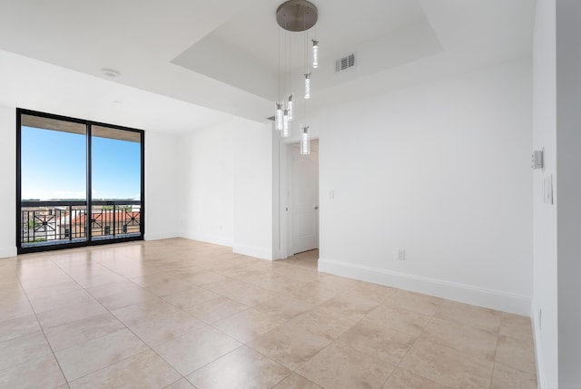 unfurnished room with light tile patterned floors and a tray ceiling