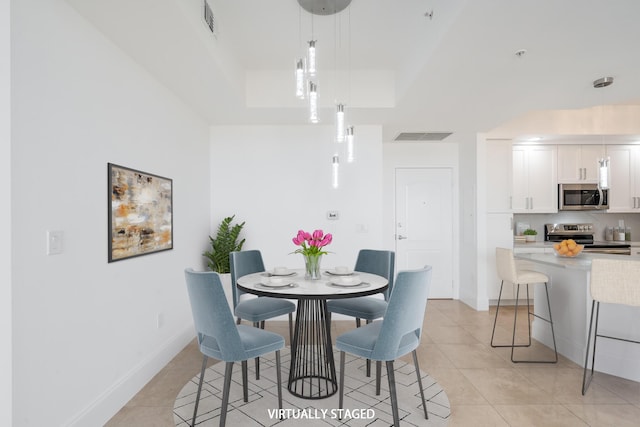 dining room with light tile patterned floors and a raised ceiling