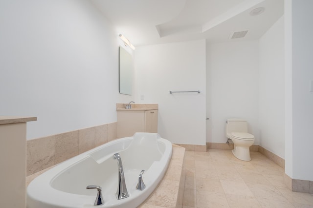 bathroom with tiled tub, vanity, and toilet