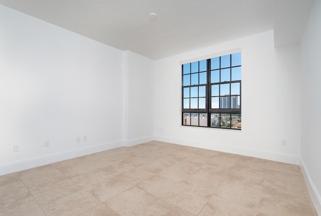 tiled empty room featuring a textured ceiling