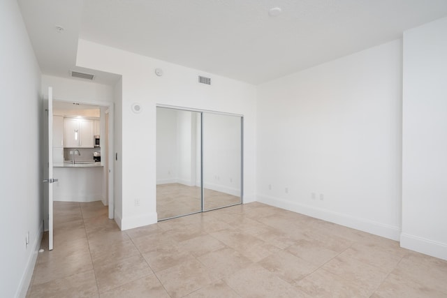 unfurnished bedroom featuring light tile patterned floors, a closet, and sink