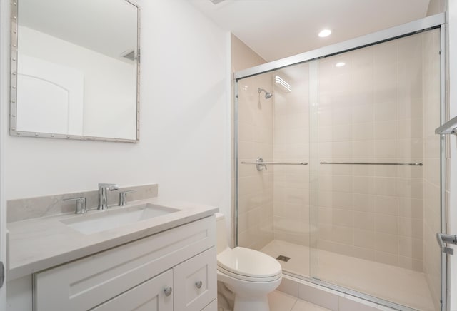 bathroom featuring tile patterned flooring, vanity, toilet, and a shower with door