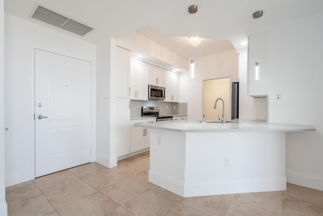 kitchen with sink, kitchen peninsula, pendant lighting, white cabinets, and appliances with stainless steel finishes