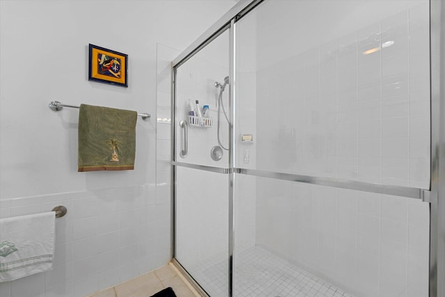 bathroom with tile patterned flooring, a shower with door, and tile walls