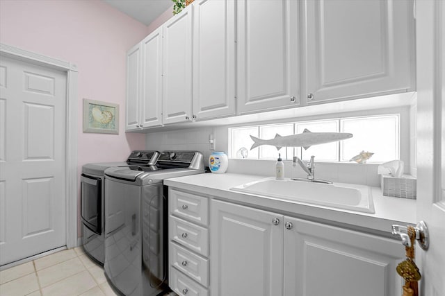 laundry area featuring washer and clothes dryer, light tile patterned flooring, cabinets, and sink