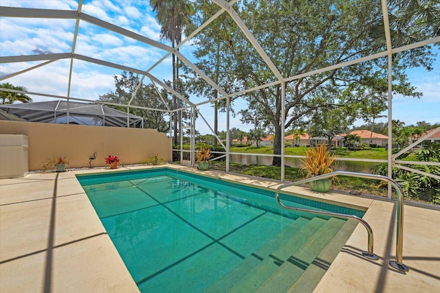 view of pool with glass enclosure, a patio area, and a water view