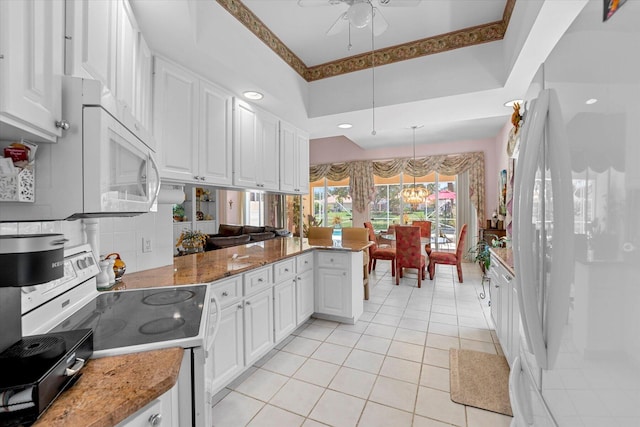 kitchen with white appliances, white cabinets, ceiling fan with notable chandelier, hanging light fixtures, and kitchen peninsula