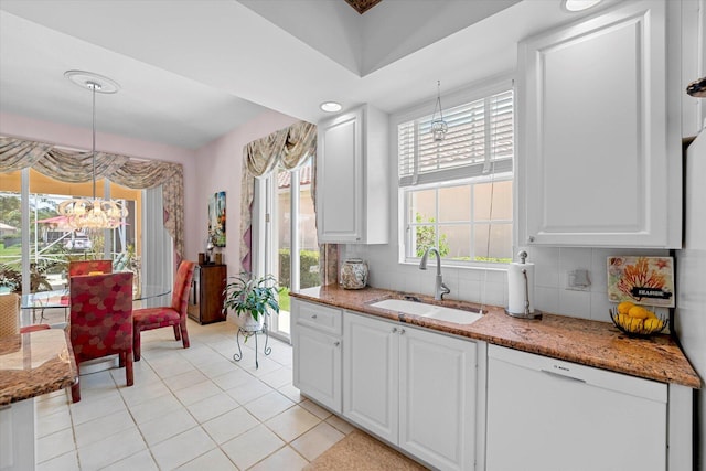 kitchen featuring backsplash, sink, a notable chandelier, white cabinetry, and hanging light fixtures