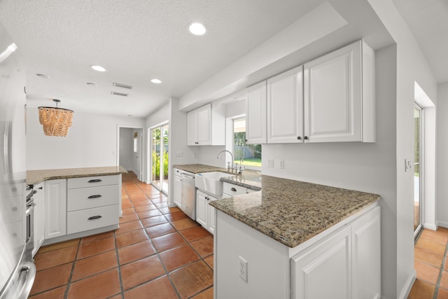 kitchen with sink, stainless steel appliances, kitchen peninsula, dark stone counters, and white cabinets