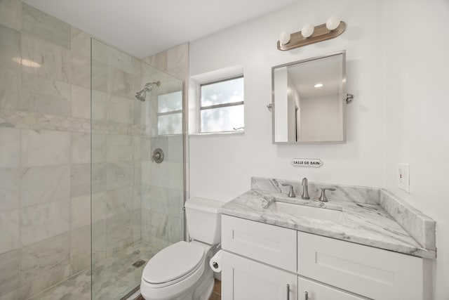 bathroom with a tile shower, vanity, and toilet